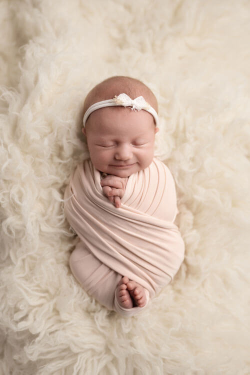Neugeborenes Mädchen, eingewickelt in ein makelloses weißes Tuch, ruht friedlich und strahlt Reinheit und Unschuld aus.